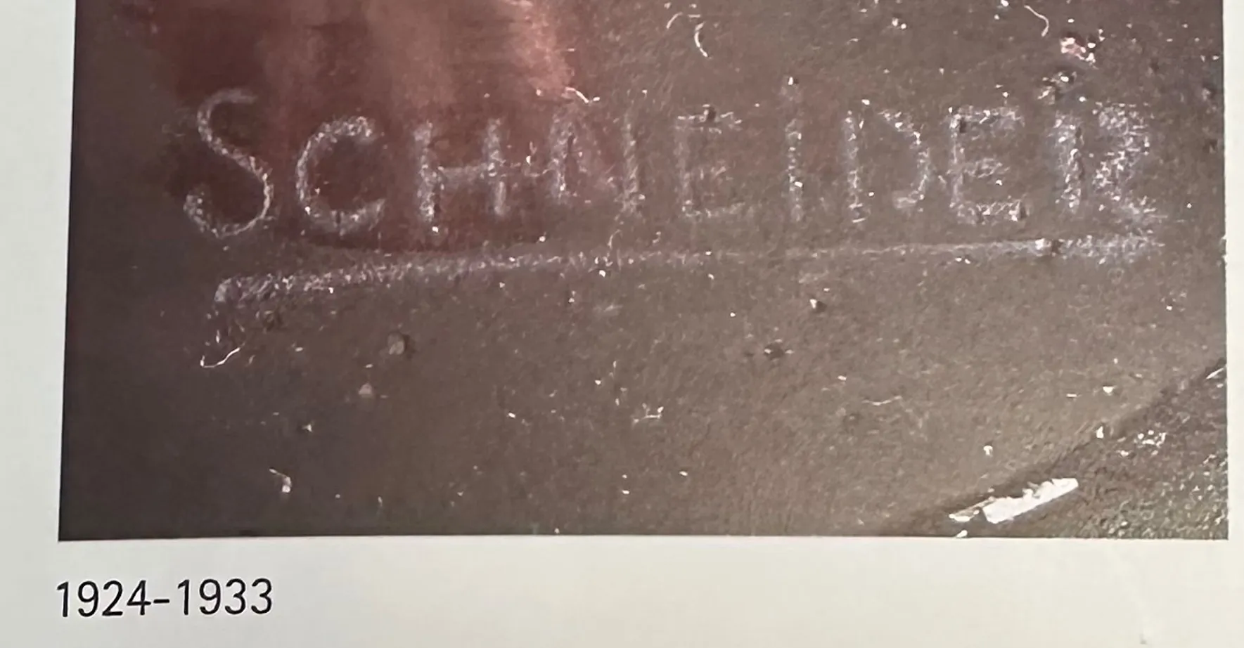 Verre signé par Schneider avec détails anciens, fond sombre.