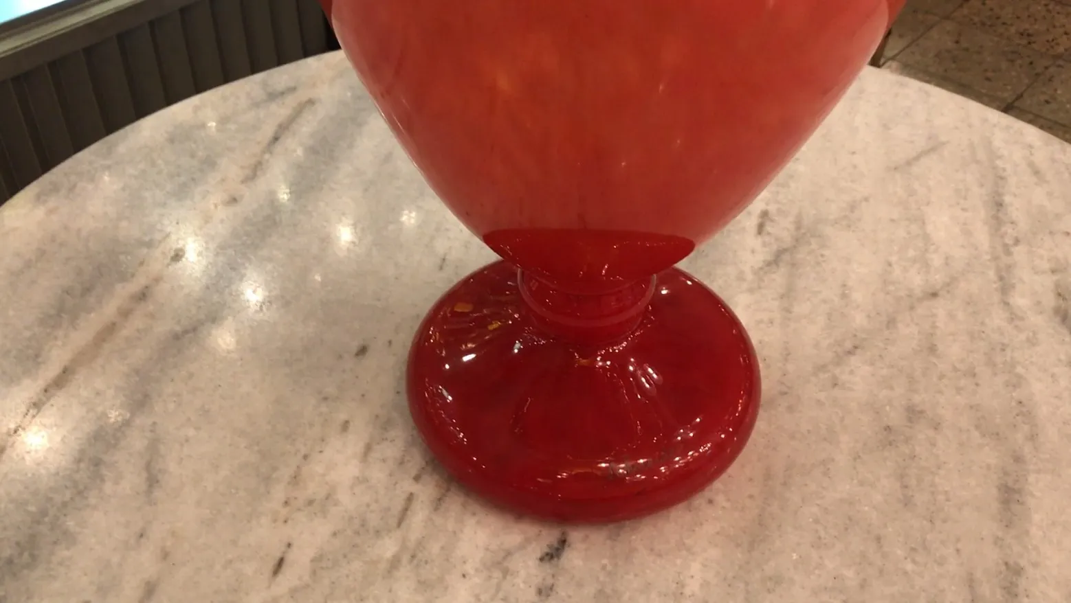 Verre ancien avec base rouge et forme élégante signé par Schneider, fond neutre.