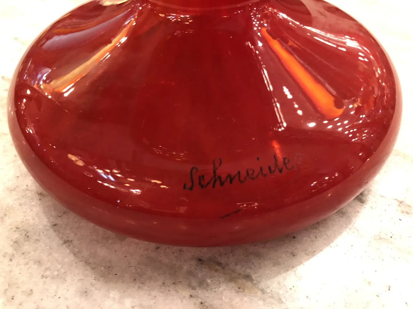 Elegant red signed glass with Schneider signature, set on a light surface.