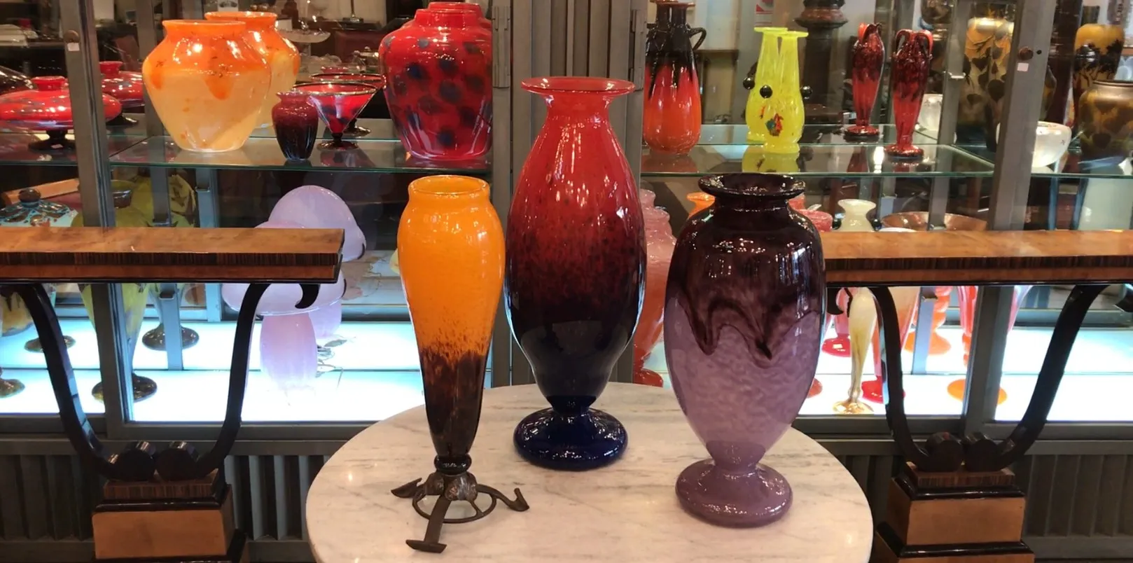 Display of antique signed Schneider glass vases in various colors.