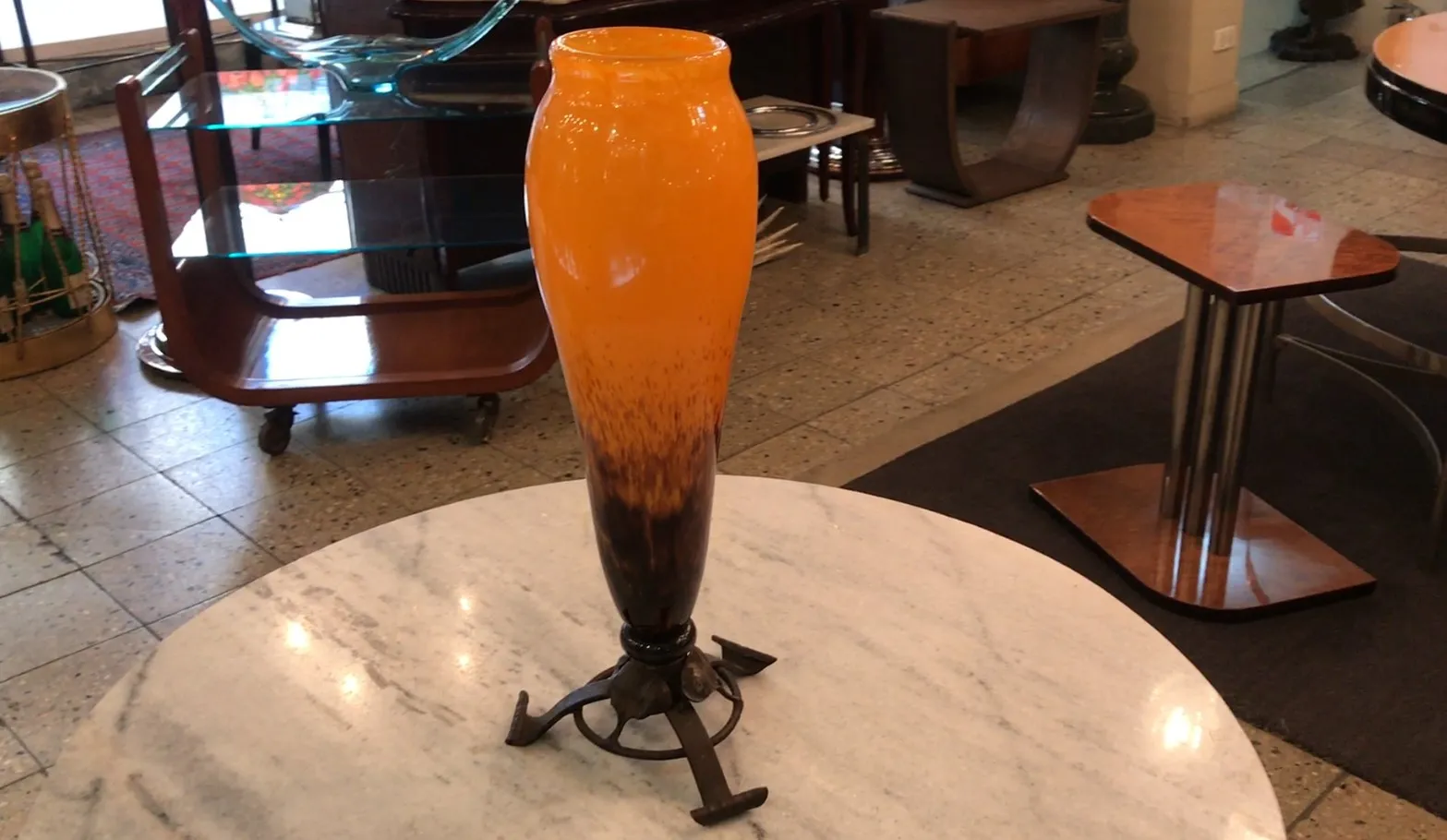 Antique vase of signed glass by artist Schneider, featuring a decorative design with orange and brown colors in a cozy setting.