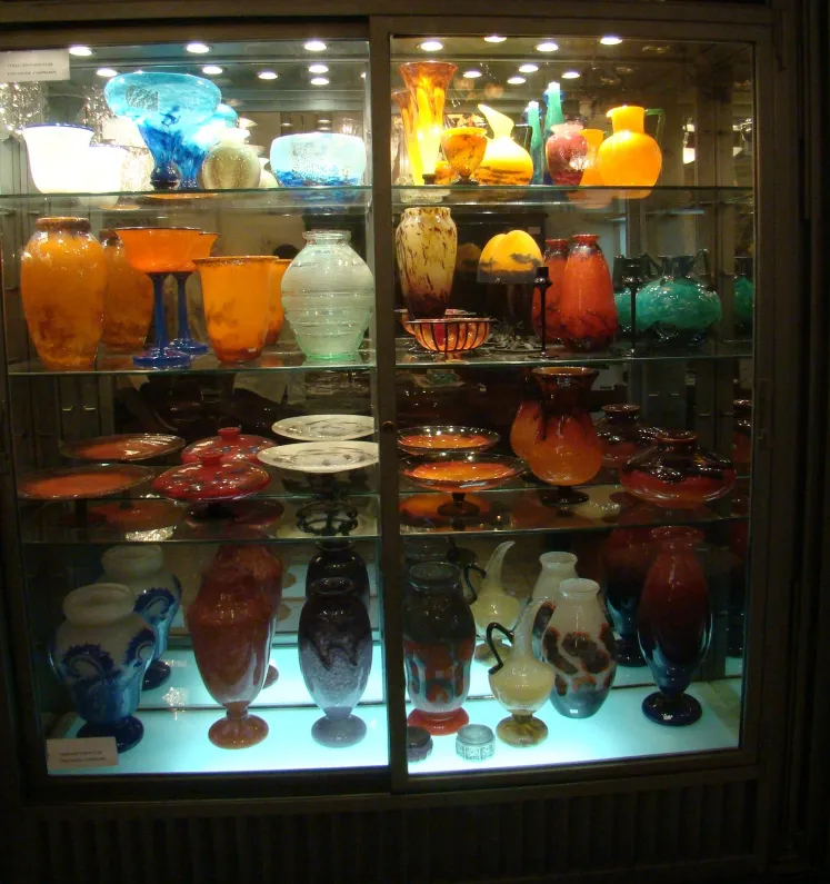 Colección de antigüedades de vidrio, incluyendo piezas firmadas por Schneider, diversas formas y colores.