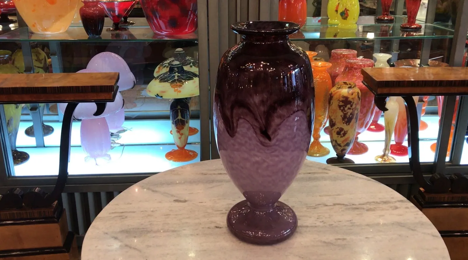 Vase en verre signé Schneider aux tons violets, entouré d'antiquités colorées.