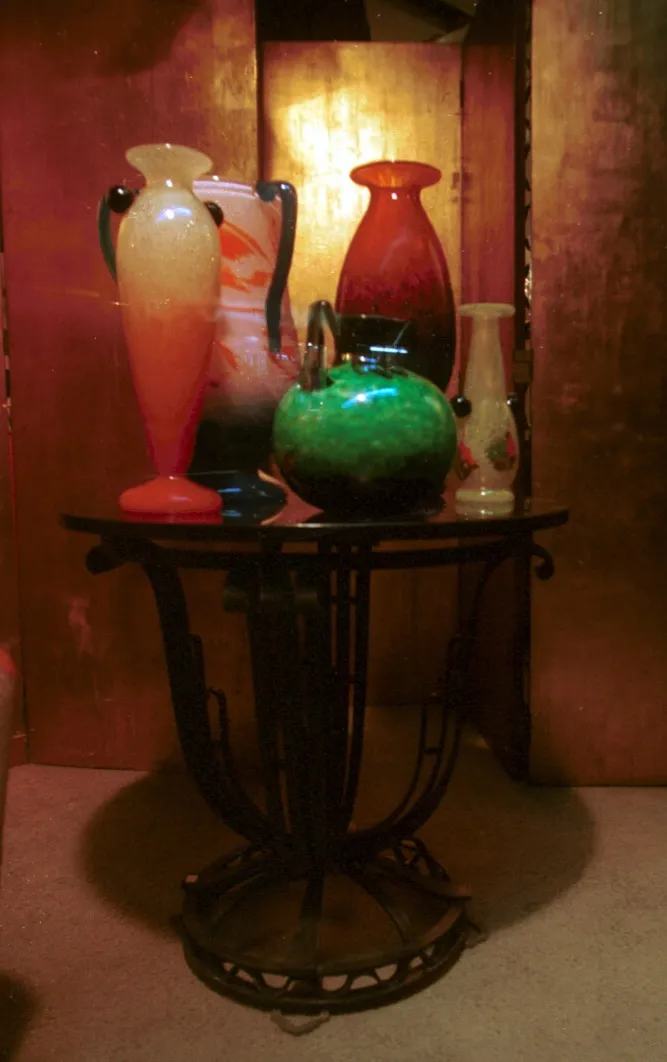 Antique signed glass in green, red, and blue. Various decorative vases in a warm setting.