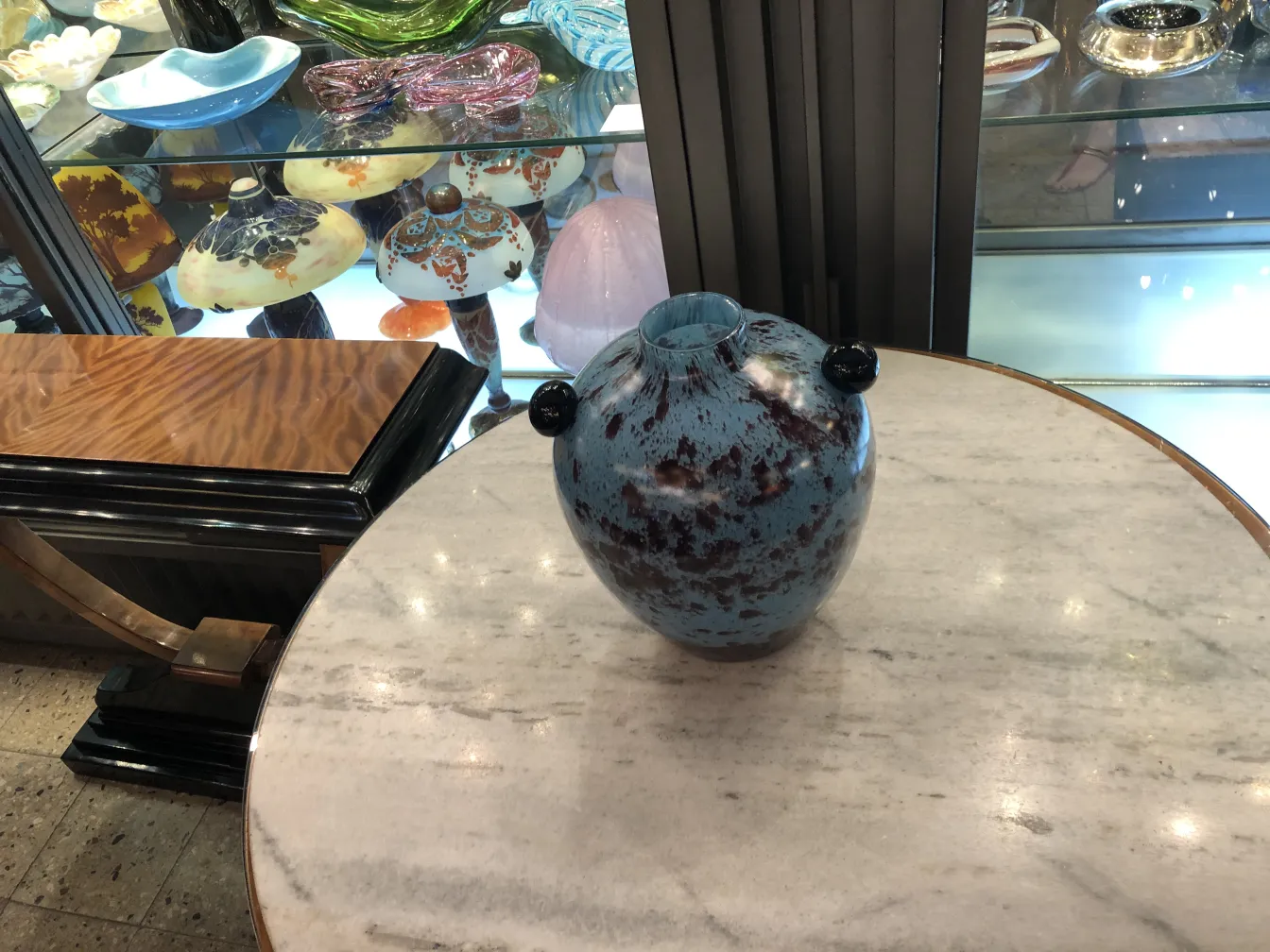 Vidrio firmado con detalles en tonos azules y rojos, ambiente de antigüedades.