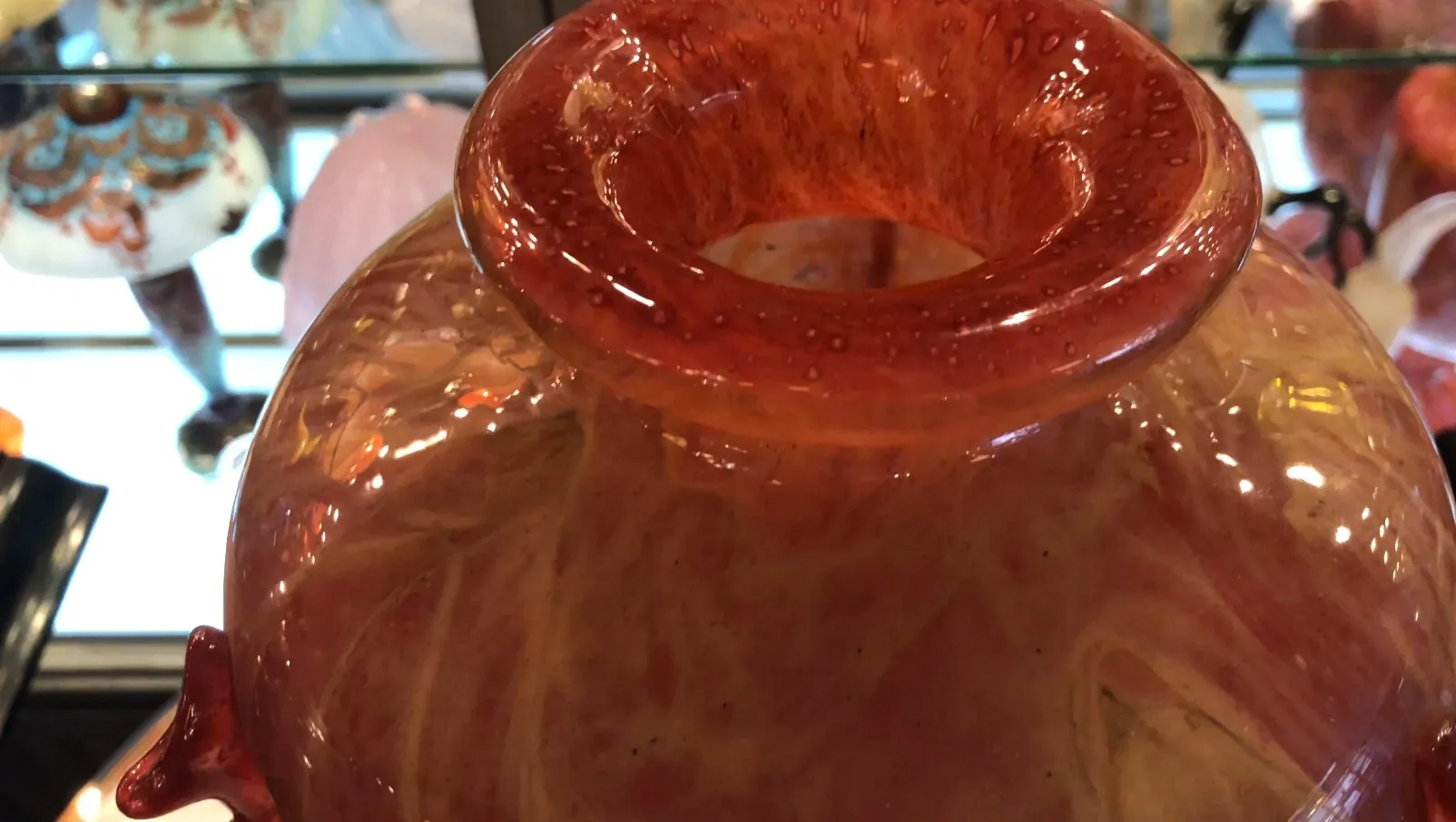 Vetro firmato antico Schneider, con design arancione e giallo, posizionato tra antichità.