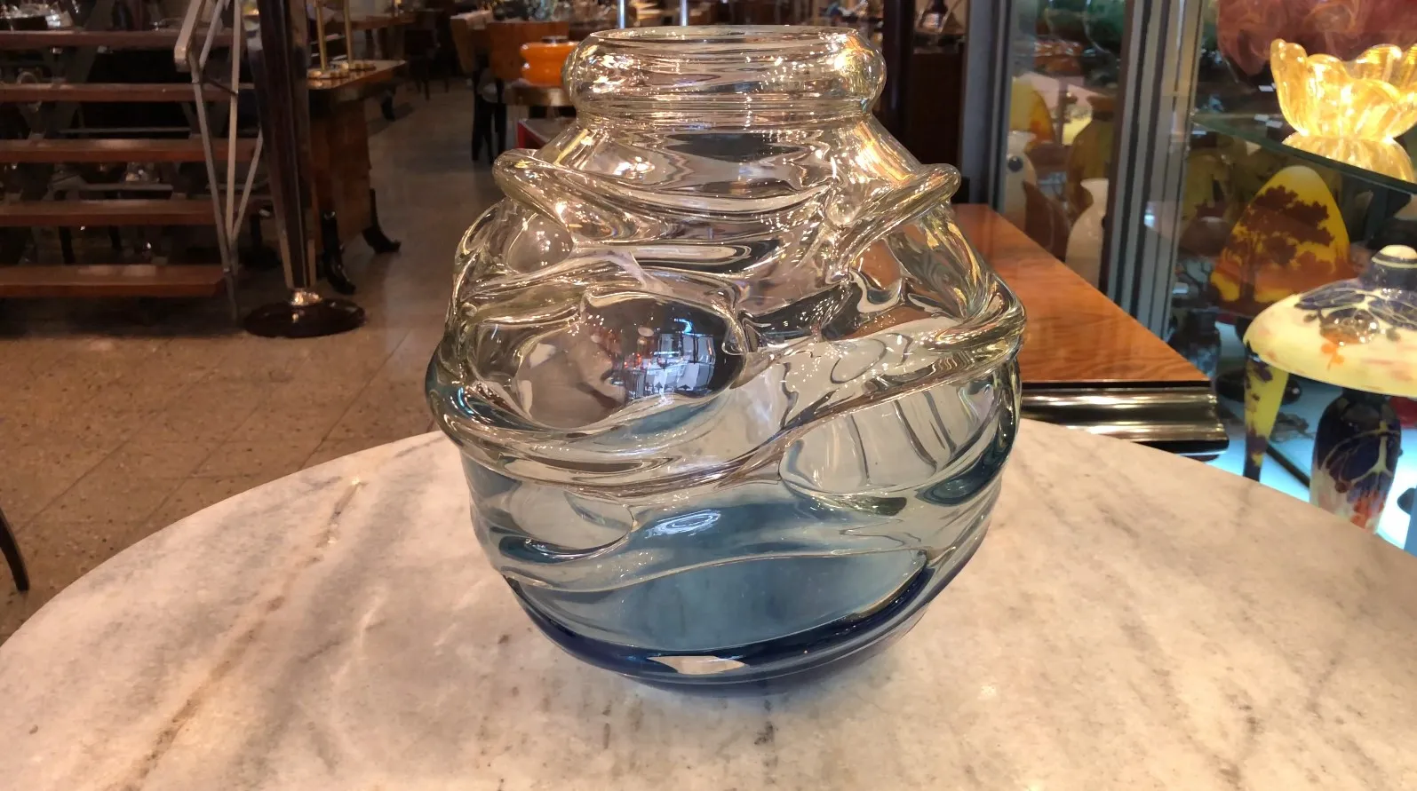 Signiertes Glas von Schneider mit fließendem Design und blauer Farbe, Antiquität. Hintergrund mit anderen dekorativen Gegenständen.