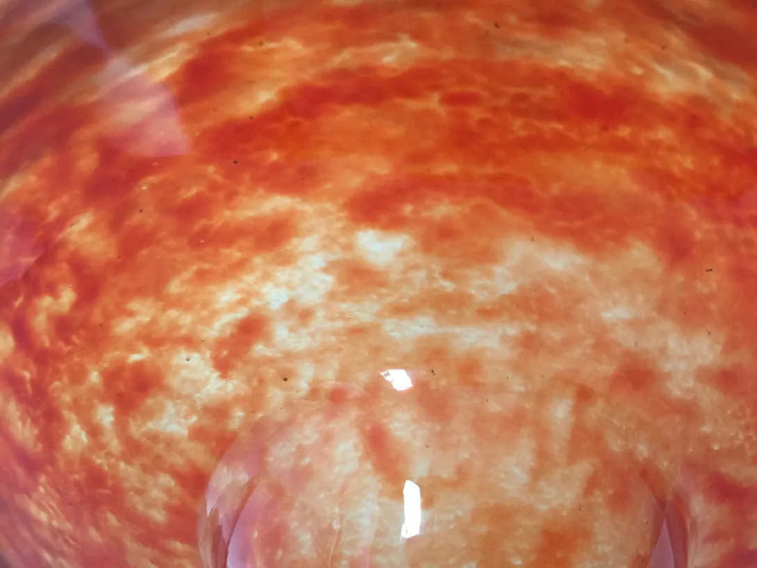 Verre signé par Schneider affichant un design décoratif dans des tons orangés et son environnement.