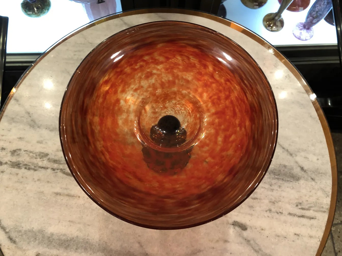 Draufsicht auf ein schönes signiertes Glas Schneider mit warmen Farbtönen im Licht.