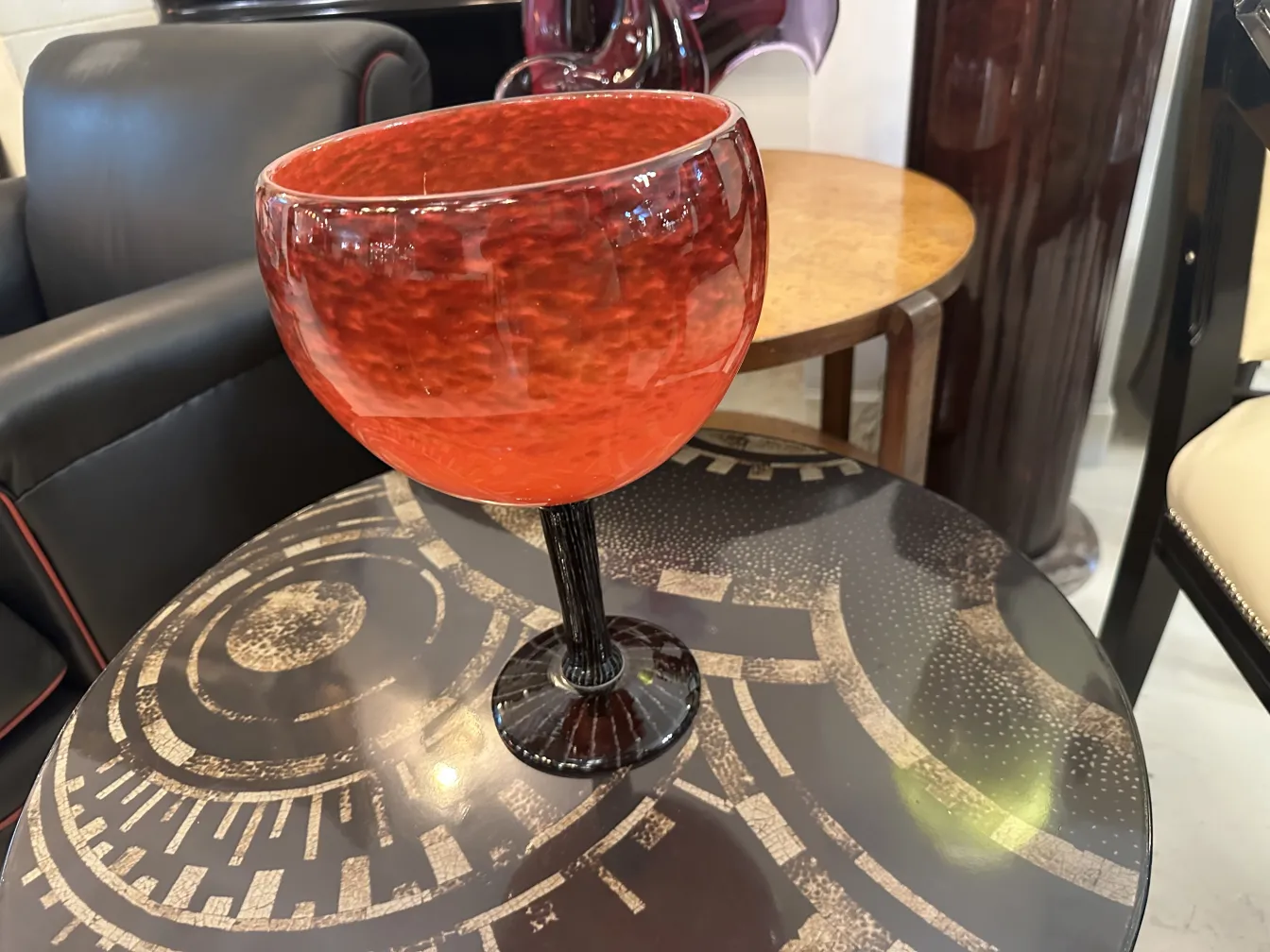 Vidro assinado vermelho em pedestal preto, ambiente elegante.