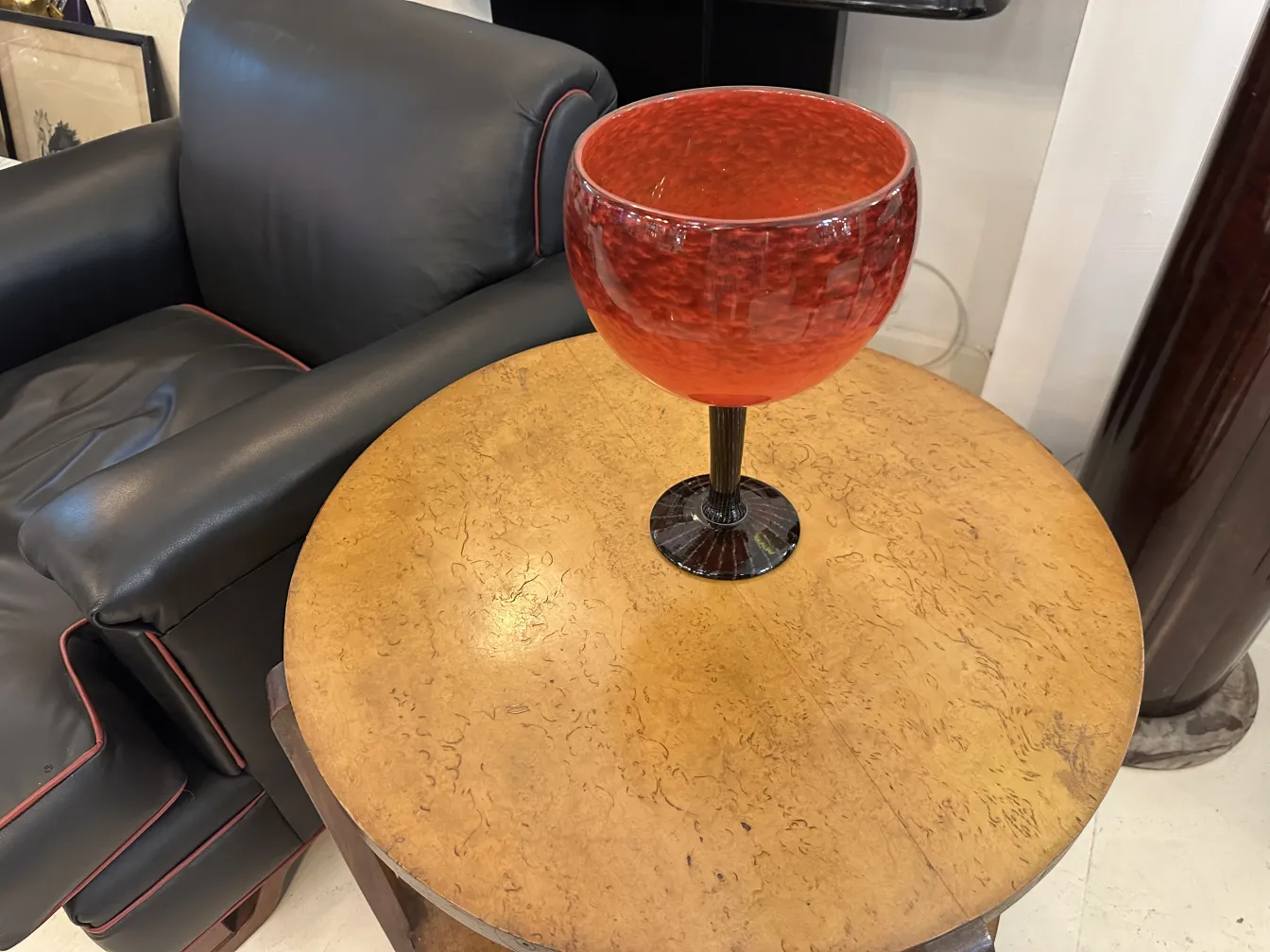 Vidro assinado Schneider em vermelho brilhante sobre mesa antiga de madeira.