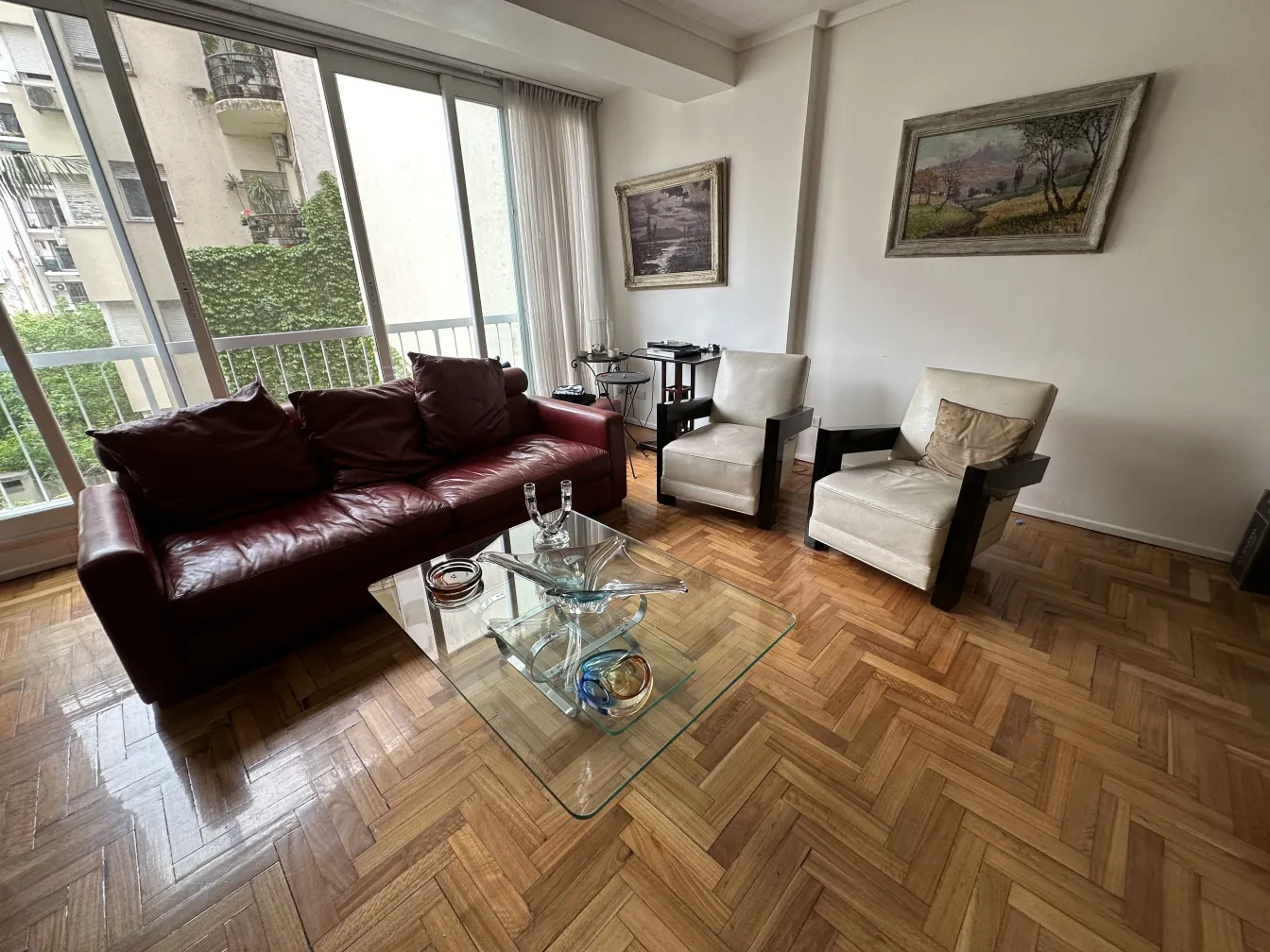 ambientación con sofá y sillones, cristal de murano sobre mesa de vidrio