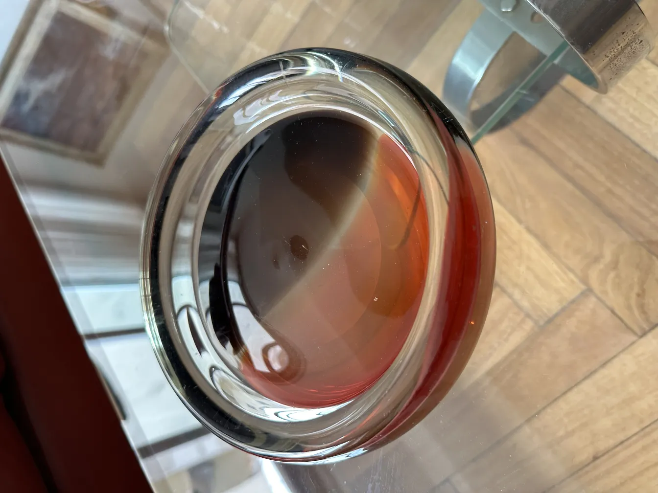 antiguo cristal de murano en forma redonda con colores rojos brillantes, en una mesa de madera clara