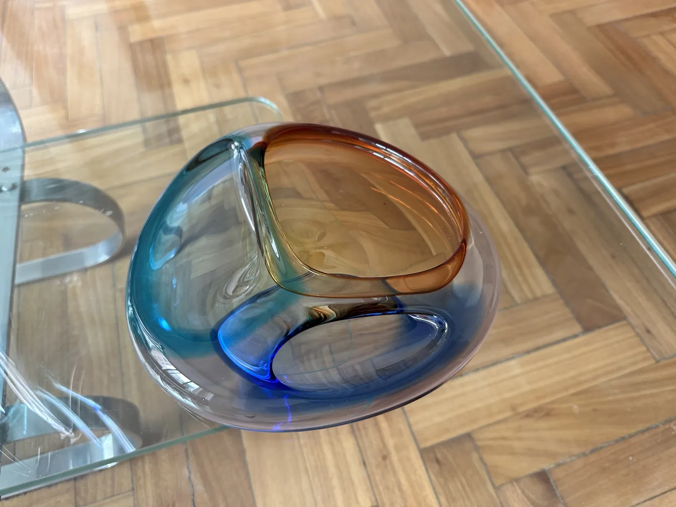 lindo cristal de murano antigo com design curvado, cores azul e marrom, colocado sobre uma mesa de vidro