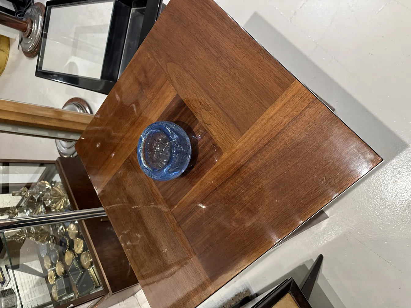 vor einem Holztisch mit einem blauen Murano-Glas