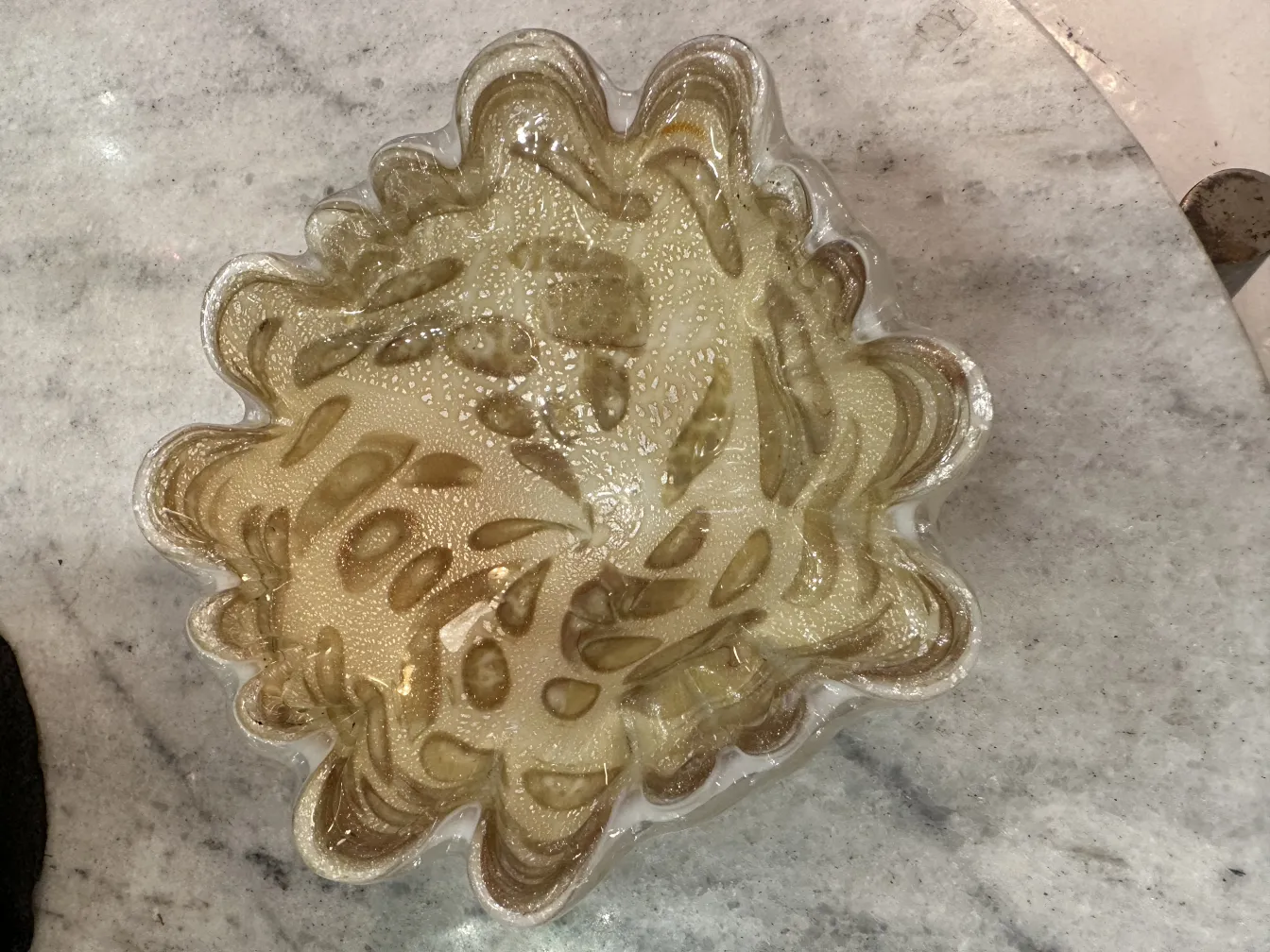 Antigüedad decorativa de cristal de Murano con detalles ondulados, dorados y texturizados sobre fondo claro.