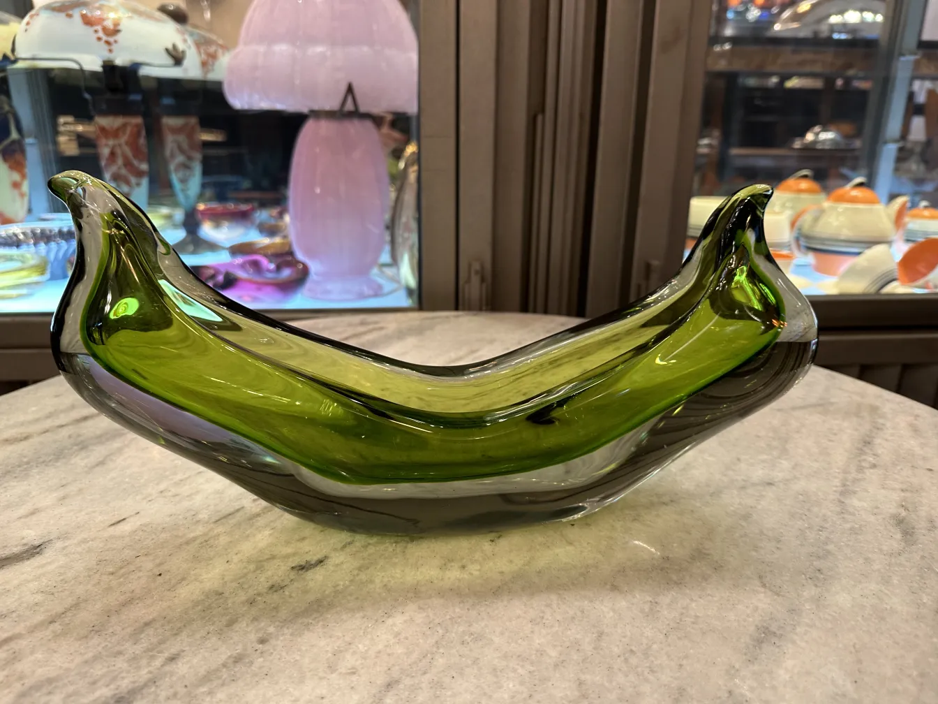 Antikes Murano-Glas in Bananenform, grün und hellblau, in einer antiken Umgebung.