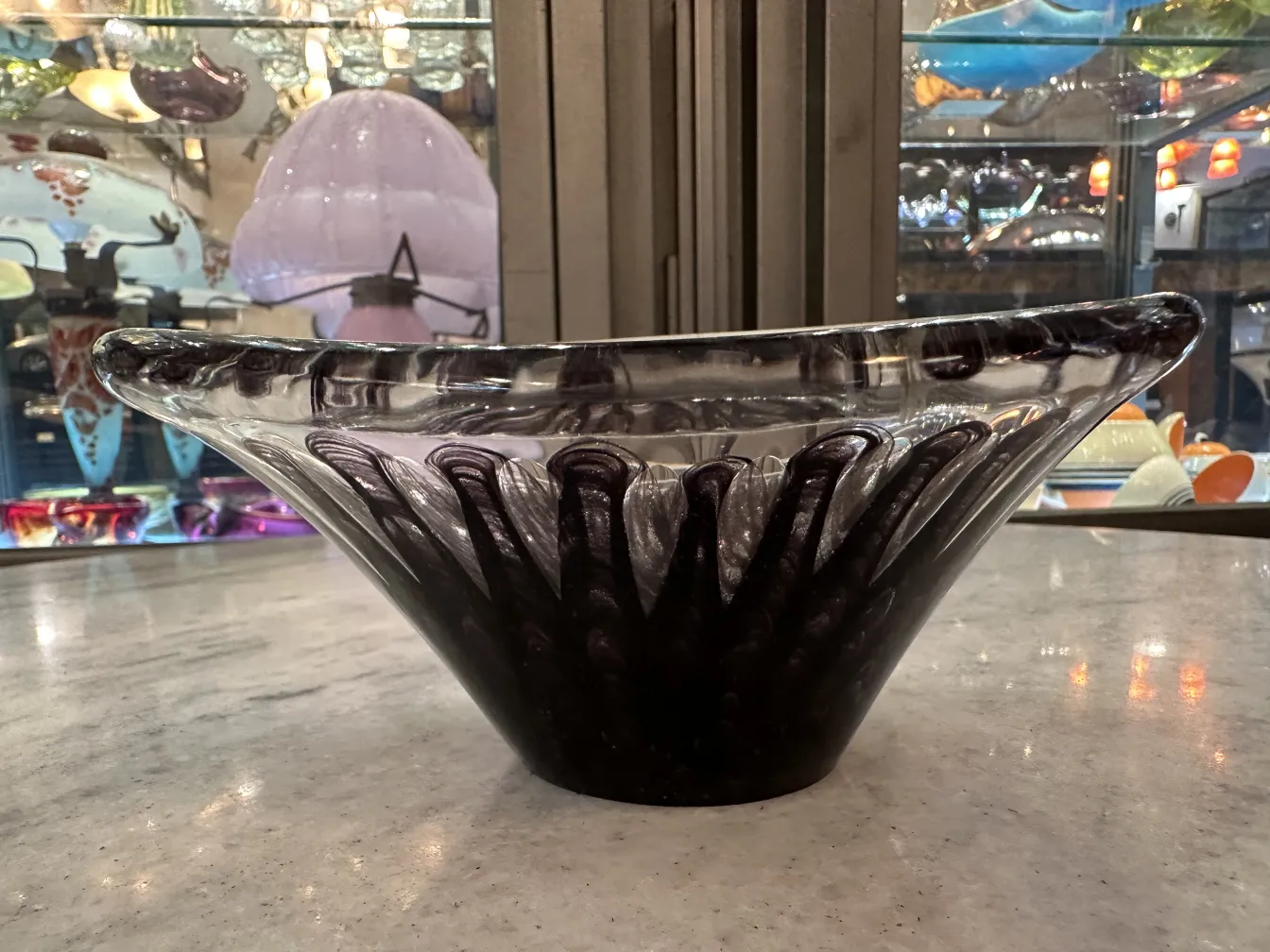 murano glass bowl with wave pattern, black base, in a lit environment
