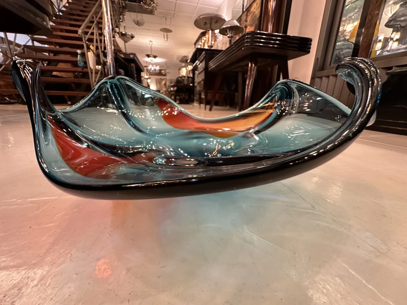 Beautiful murano glass piece with wavy shape and vibrant colors in an antique setting.
