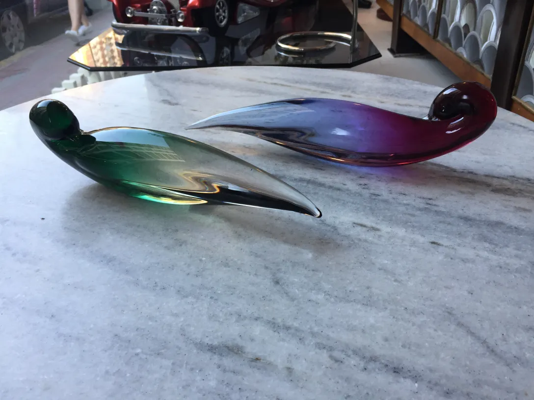 two antique murano glass pieces in green and purple colors on a table