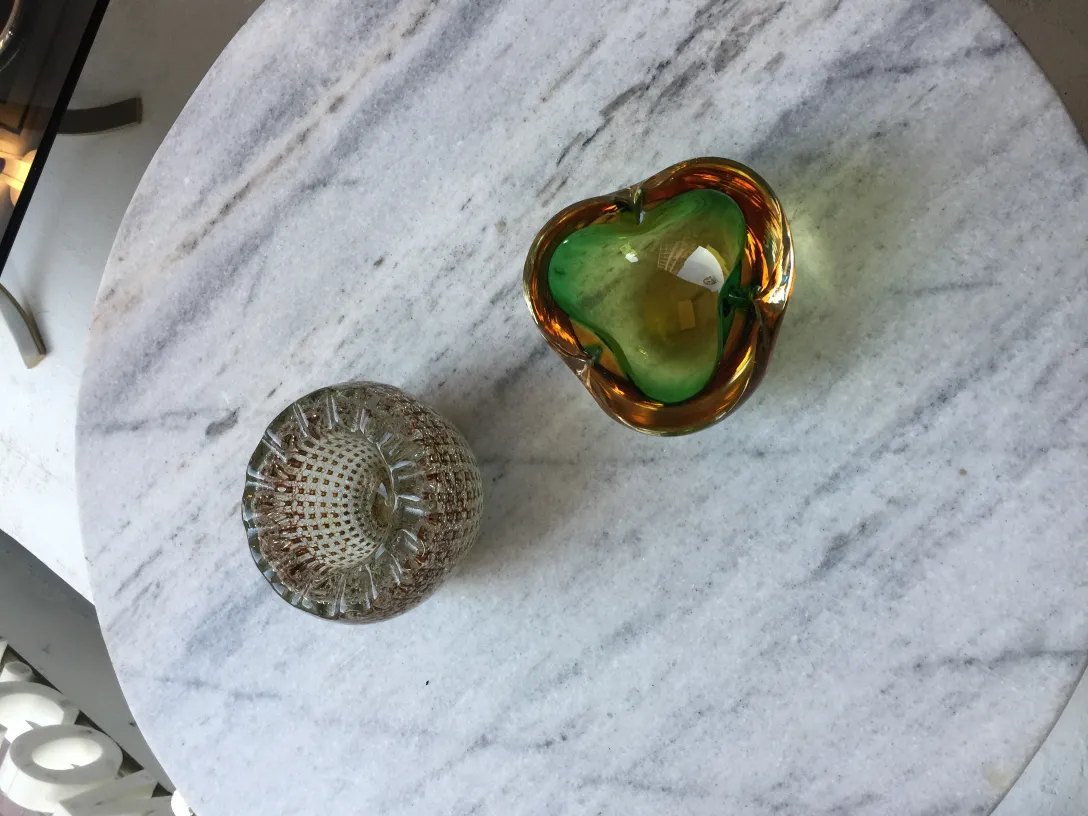 Cristal de Murano antigo em forma de coração com cores vibrantes e detalhes decorativos em uma mesa de mármore.