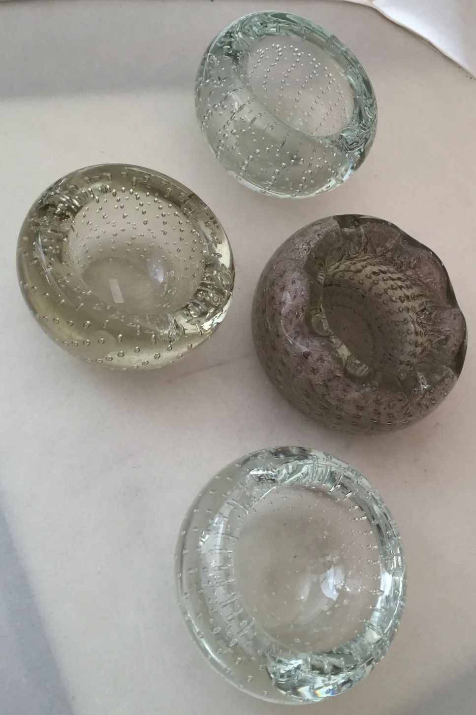four murano glass items with bubbles and various textures, featuring light colors and rounded shapes