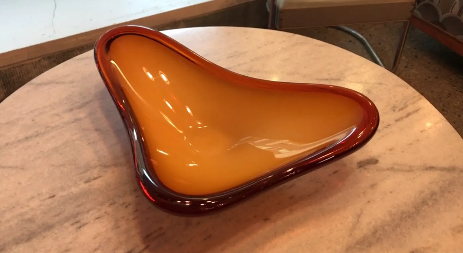 tigela de formato orgânico em tons âmbar e vermelho sobre mesa