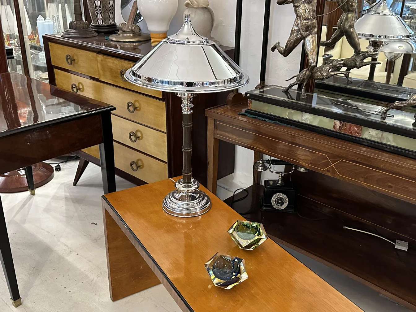 Lámpara antigua de cristal de Murano con base metálica brillante y pantallas de vidrio en un entorno decorativo.