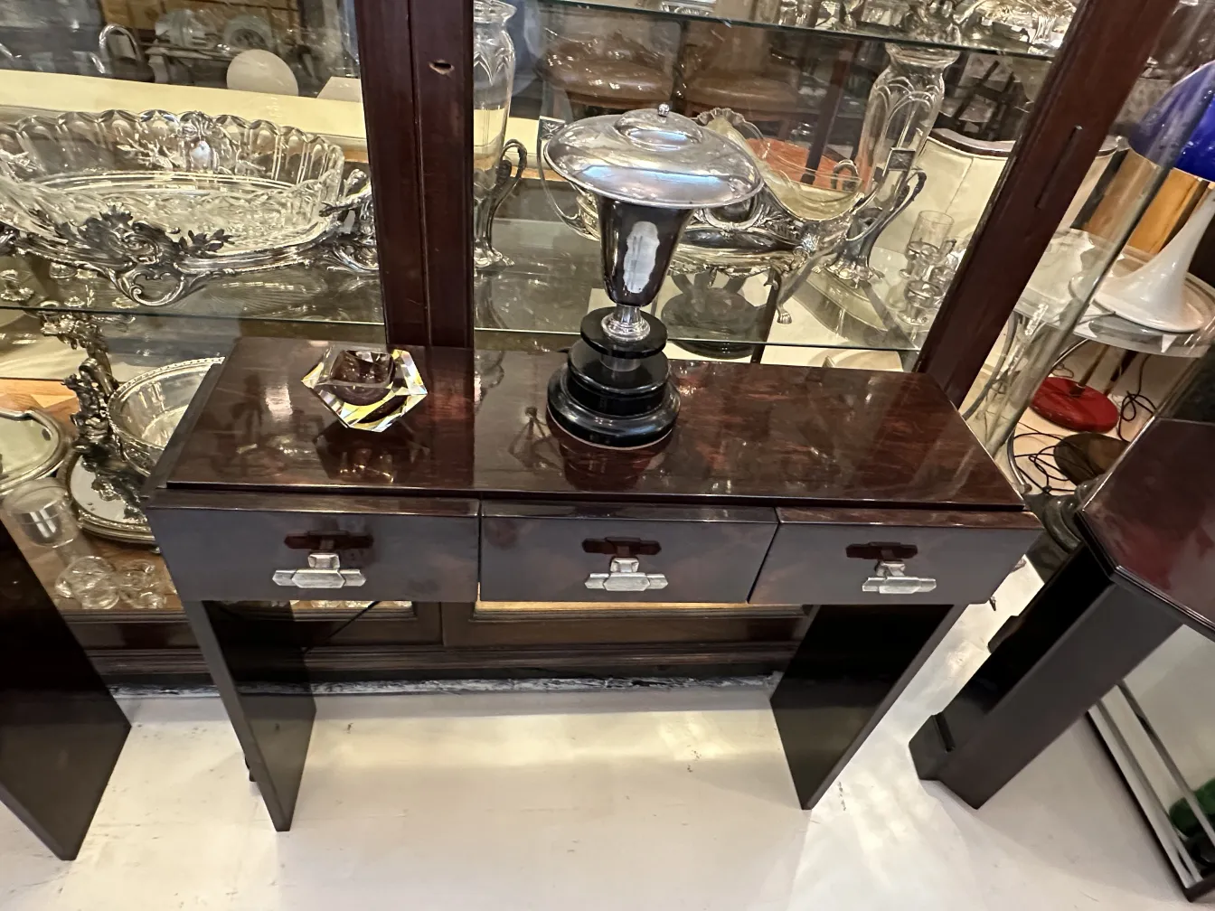 Antiguo cristal de Murano con forma decorativa sobre mesa, rodeado de otros objetos antiguos.