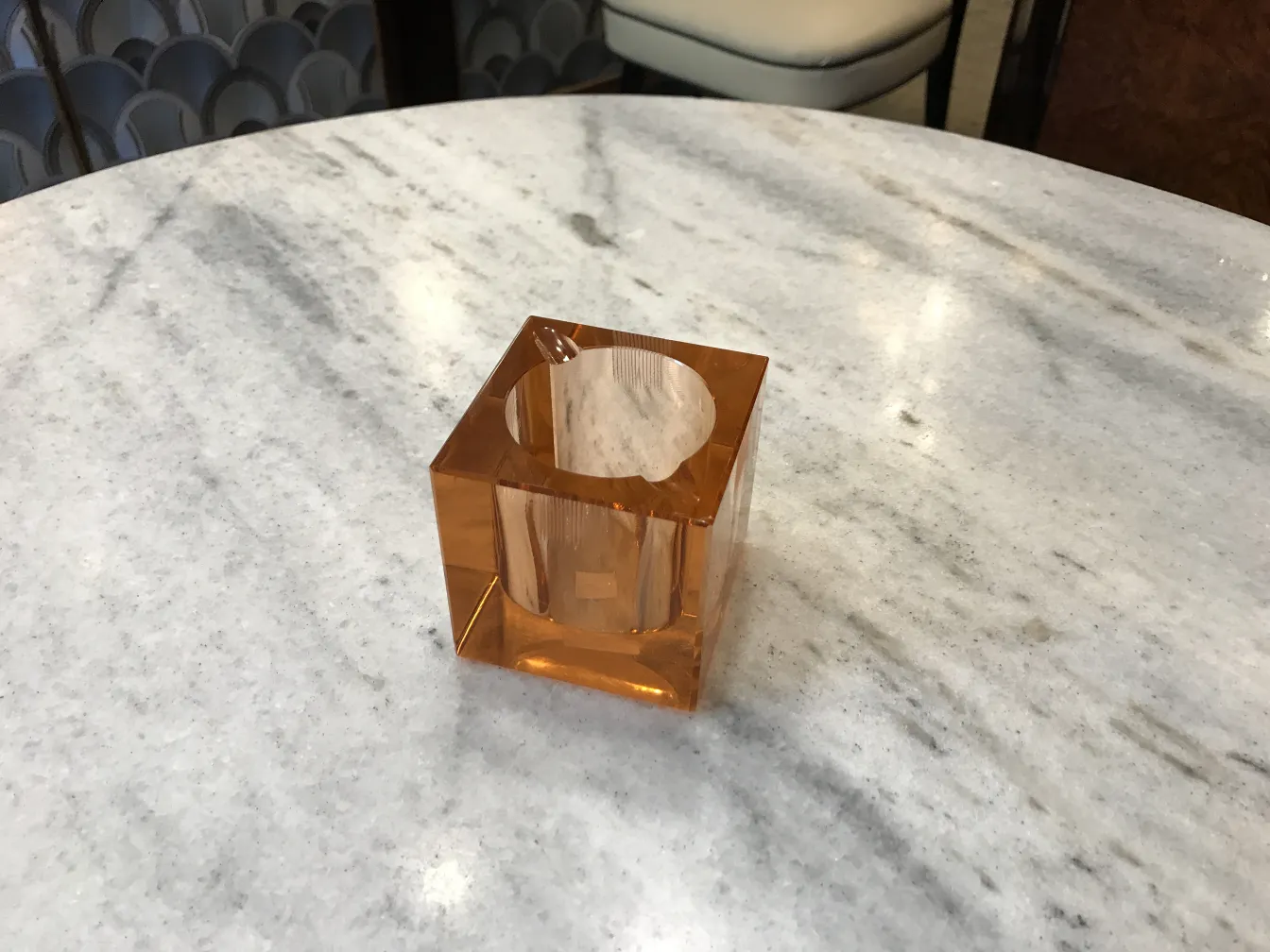 Cristal de Murano antigo em formato quadrado e cor laranja, sobre uma mesa de mármore.