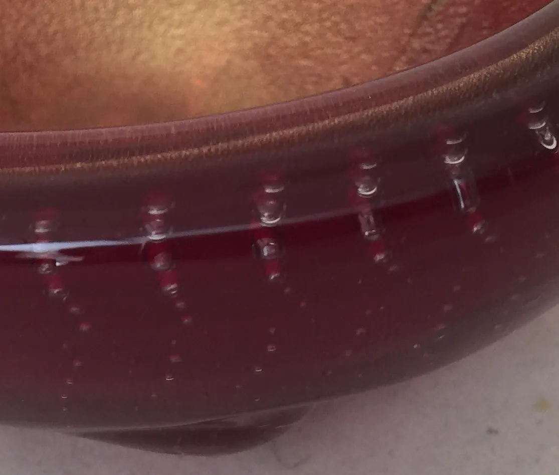 detalle de un antiguo cristal de murano con acabados rojos y burbujas de aire