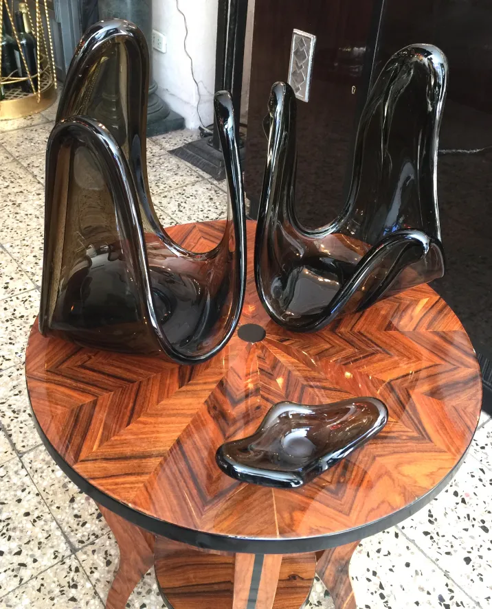 Três esculturas antigas de cristal de murano em uma mesa de madeira