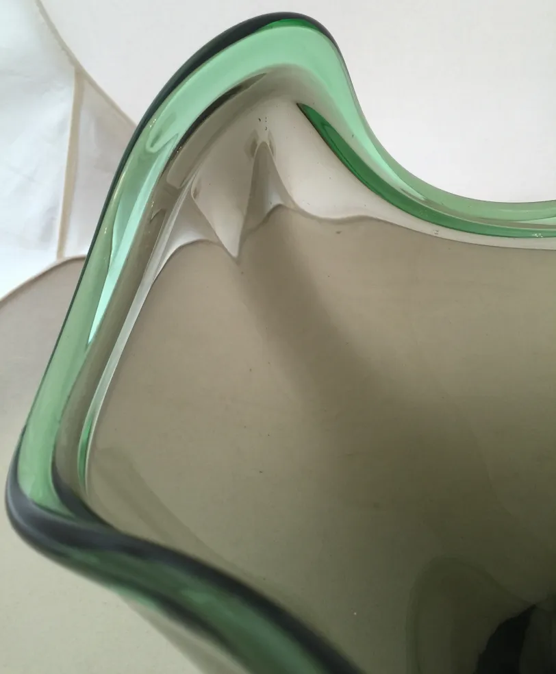 detalle de una antigua pieza decorativa de cristal de murano con bordes en verde y forma ondulada