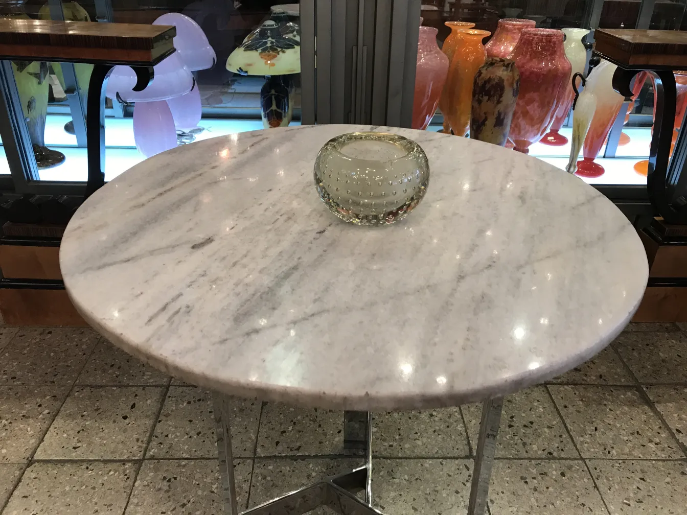 tigela de cristal de murano sobre mesa de mármore com vasos ao fundo