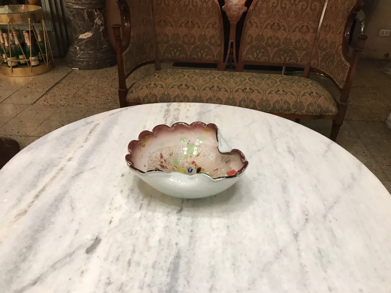 antiga peça decorativa em forma de concha de cristal de murano, com cores vibrantes, sobre mesa de mármore