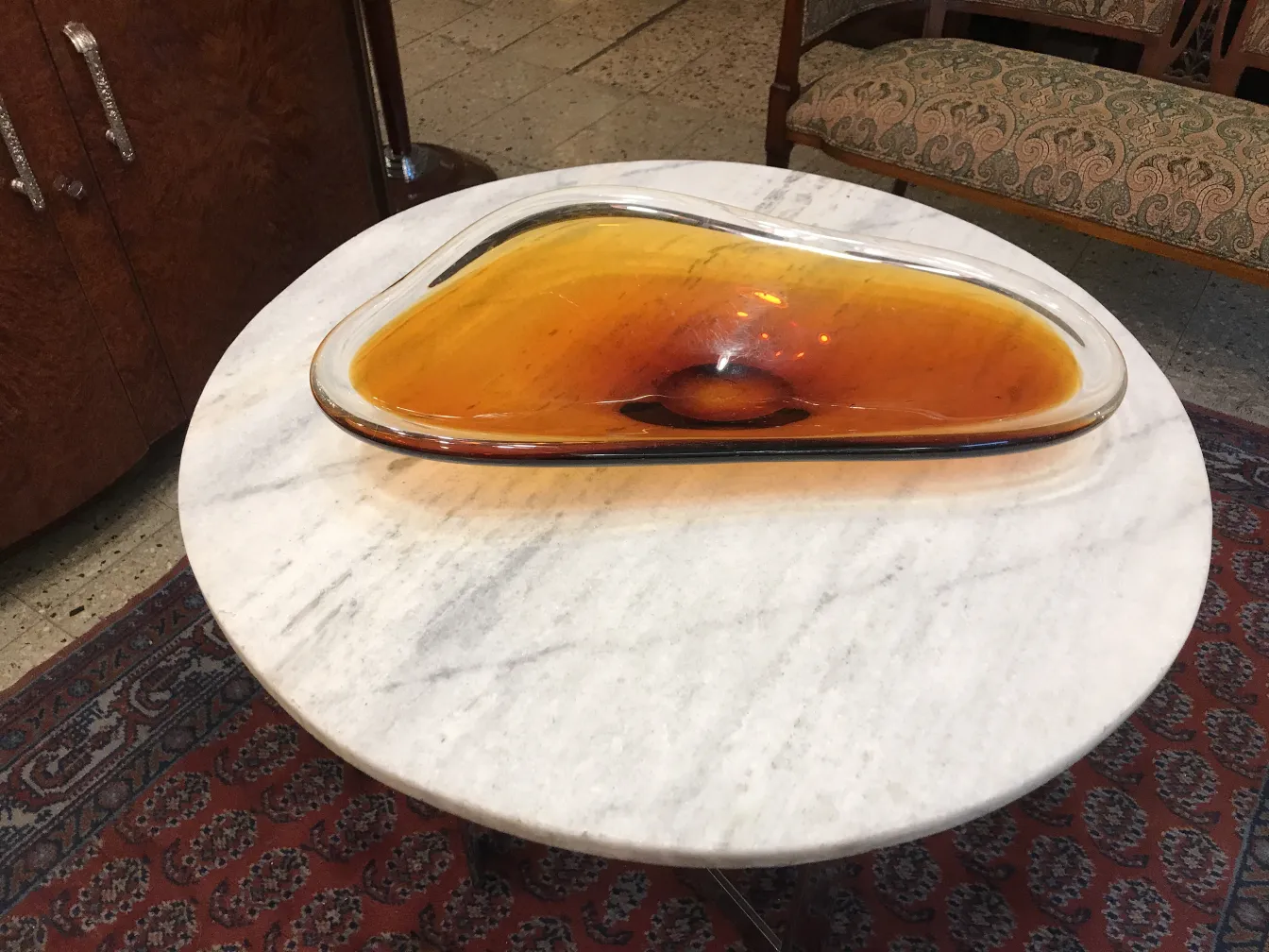 Piatto in vetro di Murano in tonalità ambrata su un tavolo in marmo.