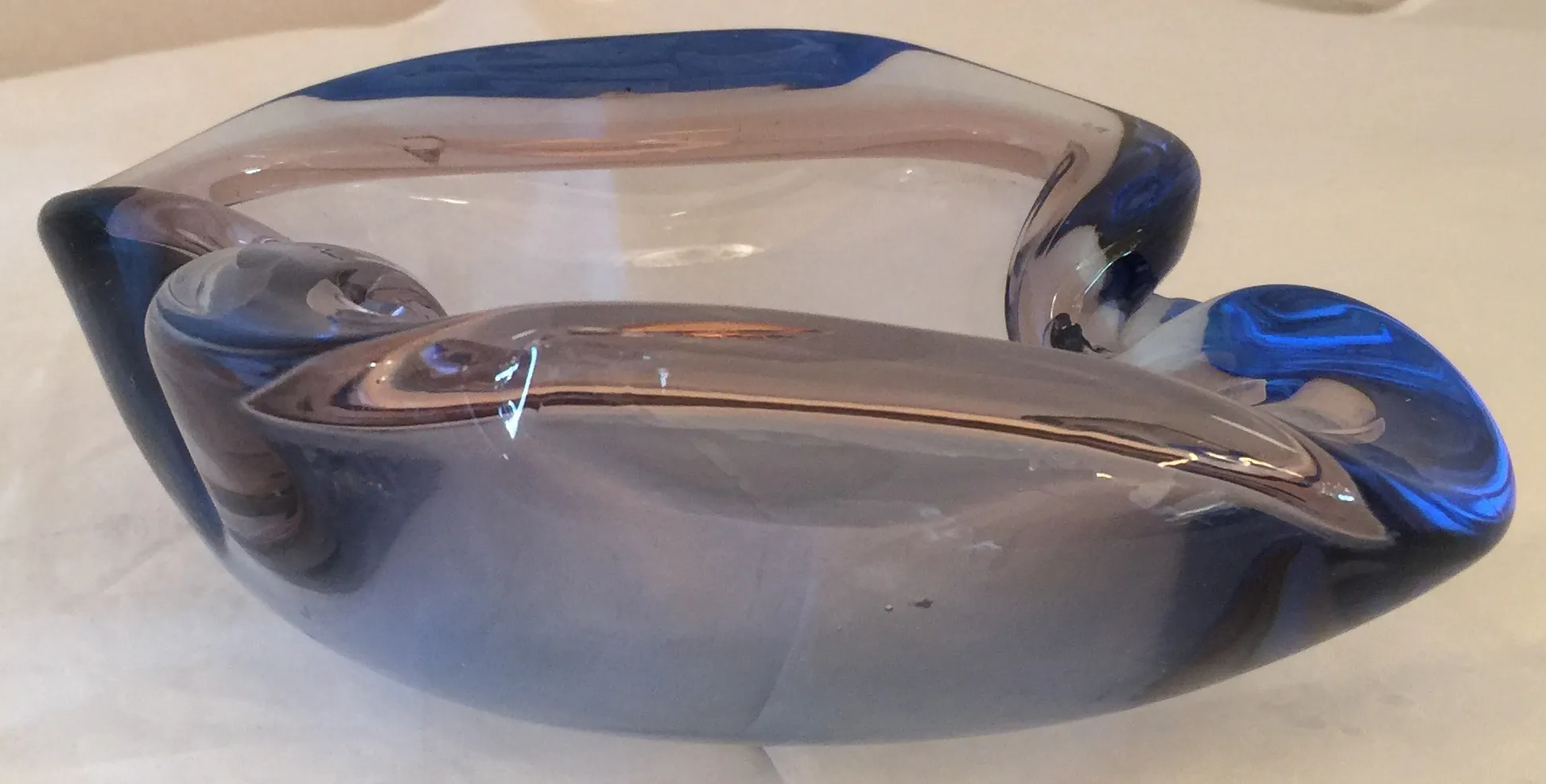 pieza de cristal de Murano en tonos azules y transparentes, con forma estilizada, sobre fondo claro