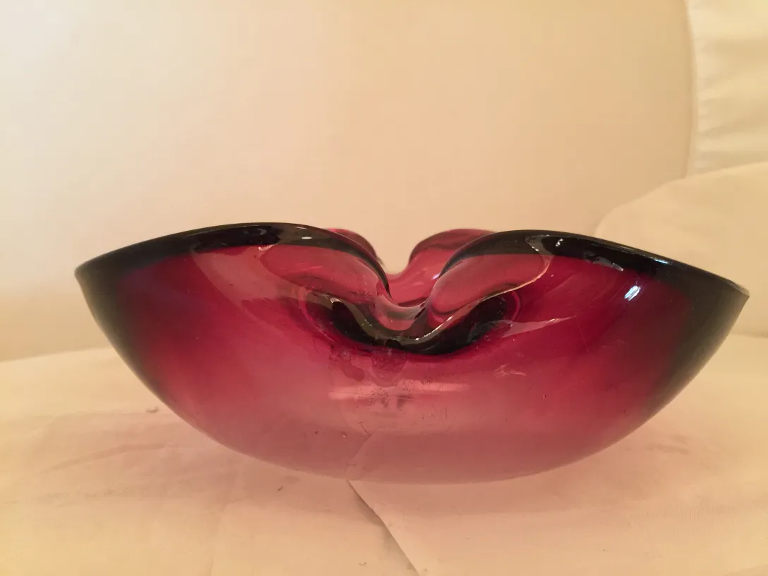 Beautiful antique murano glass with organic shape, deep red color and black edges. Brightly lit environment.