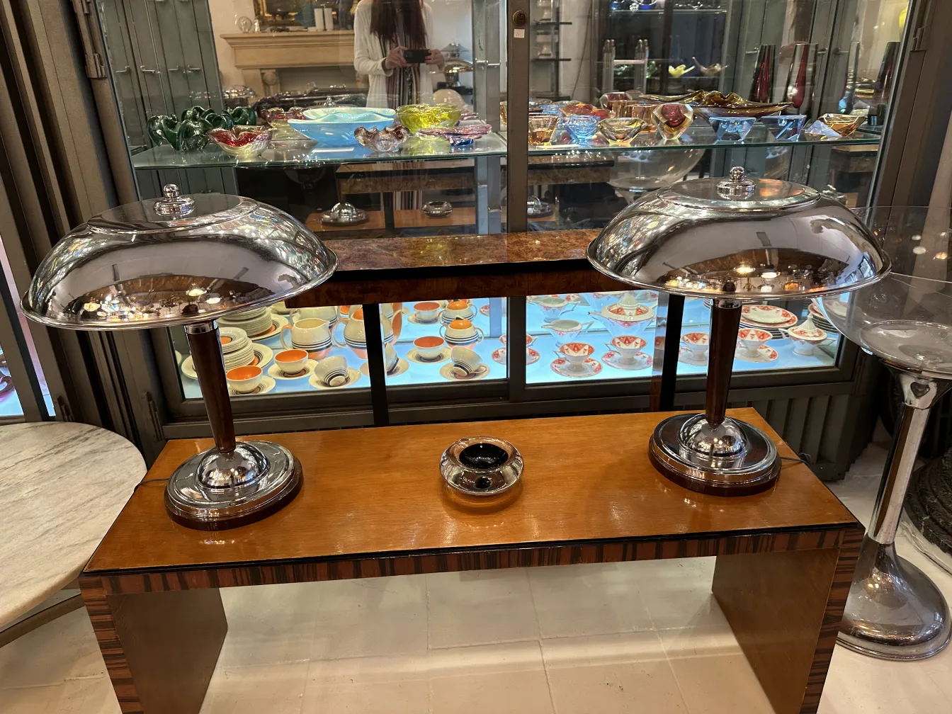 dos lámparas antiguas con base de madera y cristal de murano, fondo con platos coloridos