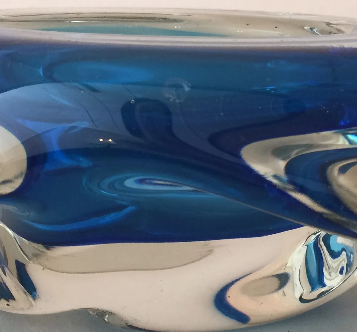 Antique Murano glass in blue tones, fluid shapes, white background.