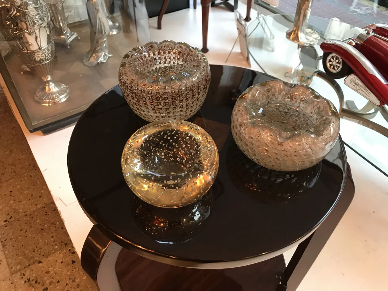 tres elementos de cristal de murano en una mesa negra, diferentes formas