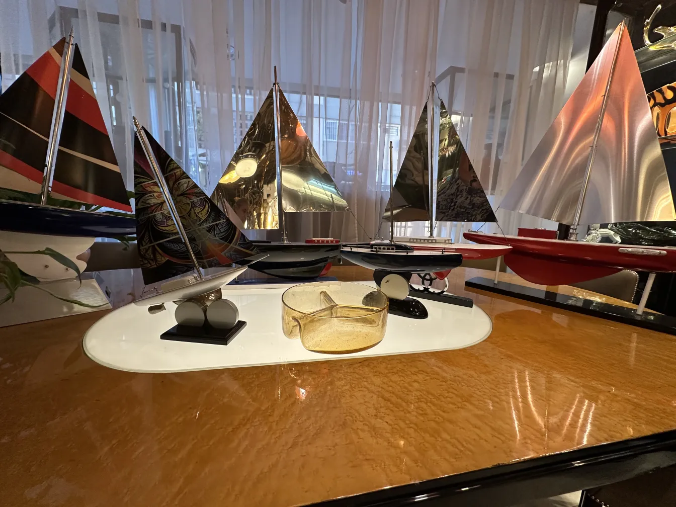 Antico vetro di Murano con dettagli decorativi lucidi, circondato da barche in miniatura.