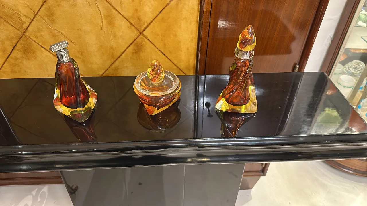 Three pieces of antique Murano glass in warm colors on a black table