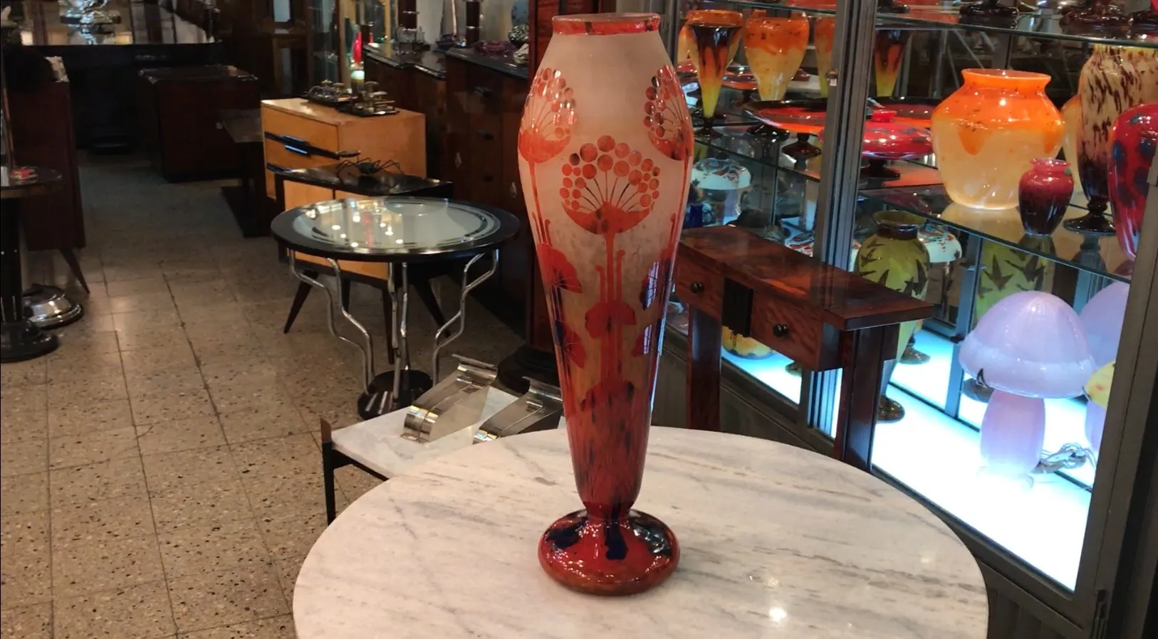 Vaso in vetro firmato con decorazioni floreali in un ambiente antico.