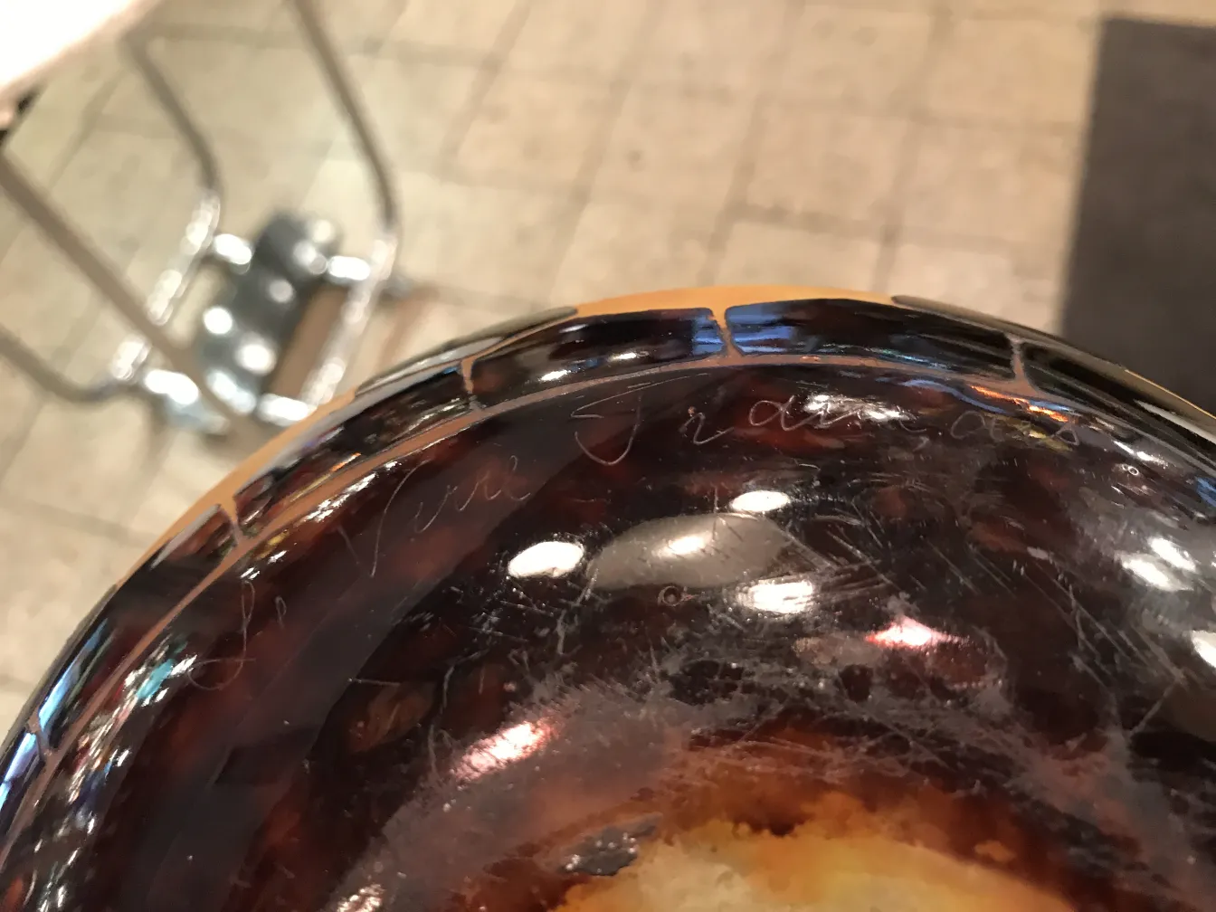 Ein antikes Glas mit sichtbarer Unterschrift von Le Verre oben, unscharfer Hintergrund.