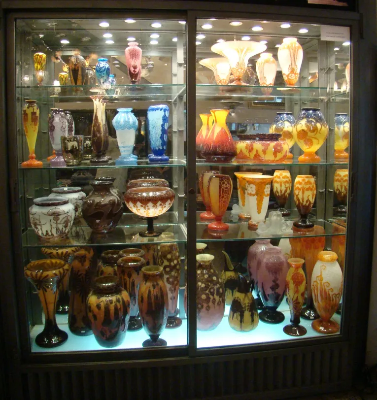 Vitrine com antiguidades, vários itens de vidro coloridos.