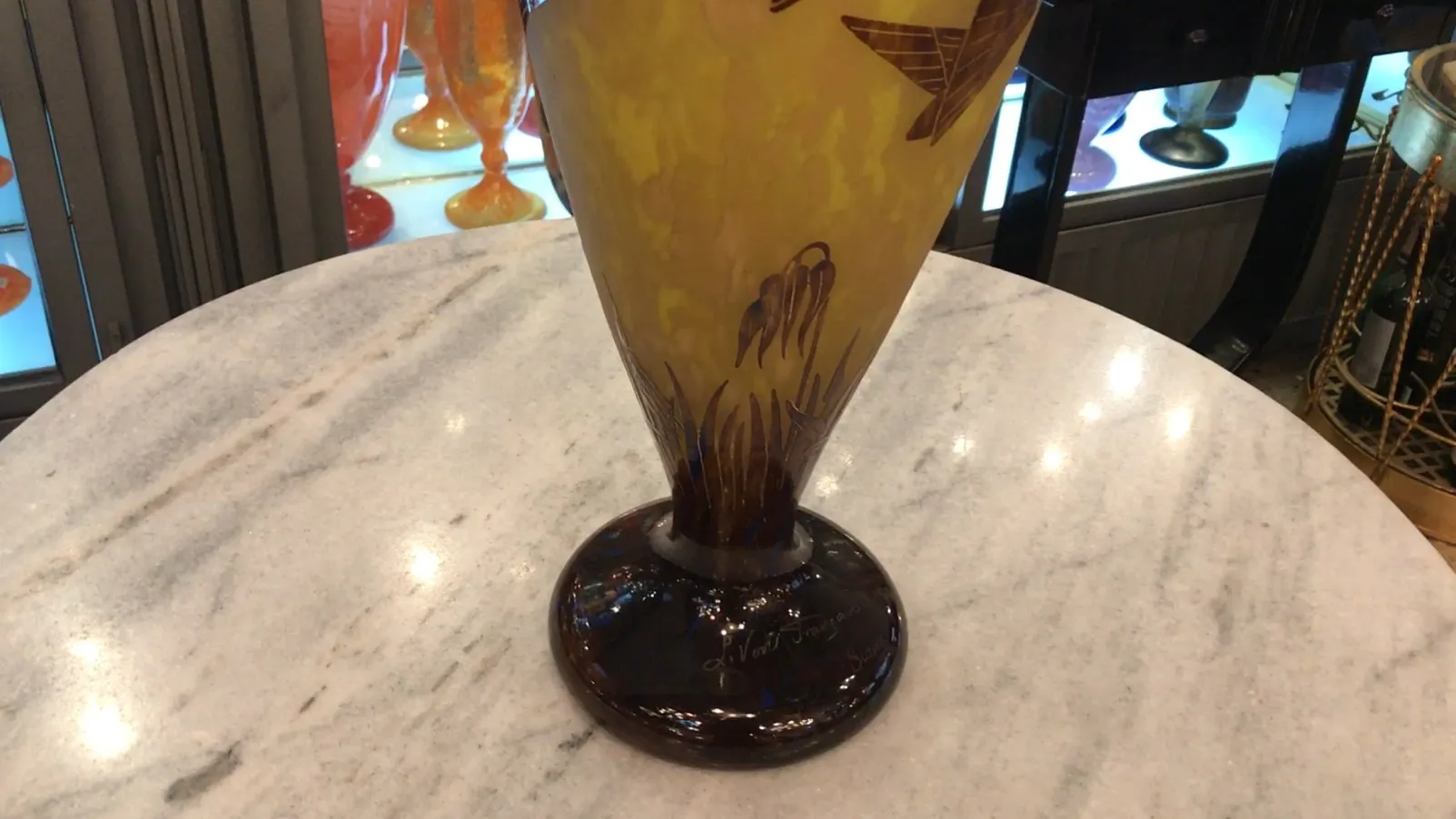 Vista lateral de um vidro antigo assinado Le Verre com decoração floral.