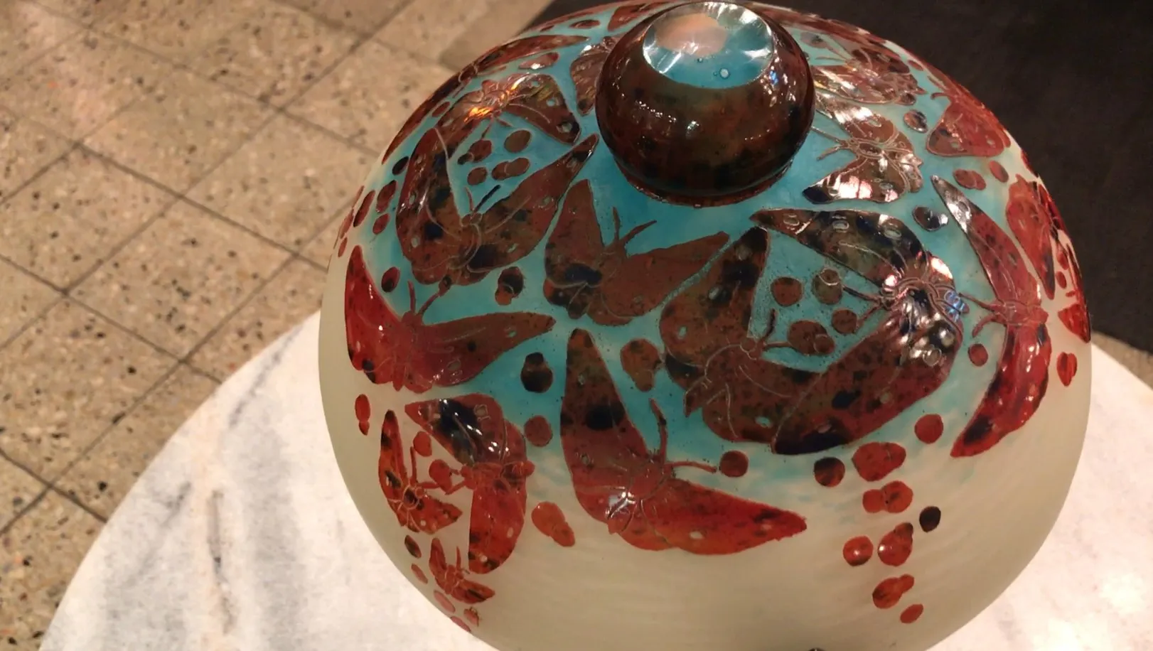 Vidrio antiguo firmado Le Verre con decoración de mariposas en tonos cálidos.