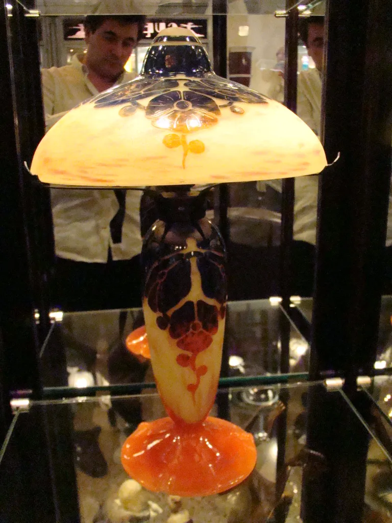 Lampada antiga vidro assinado Le Verre com cores vibrantes em exibição iluminada.