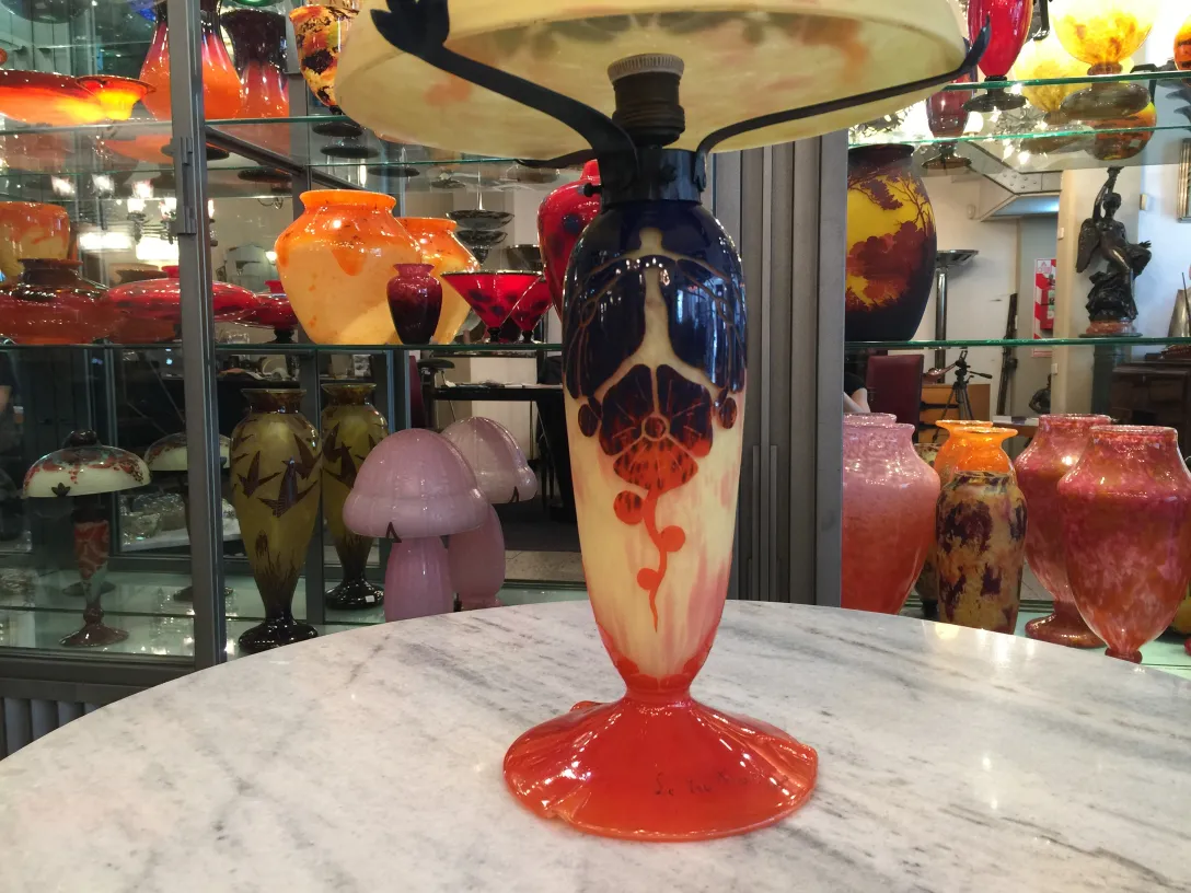 Vintage lamp with signed Le Verre glass base, background with more glass items.